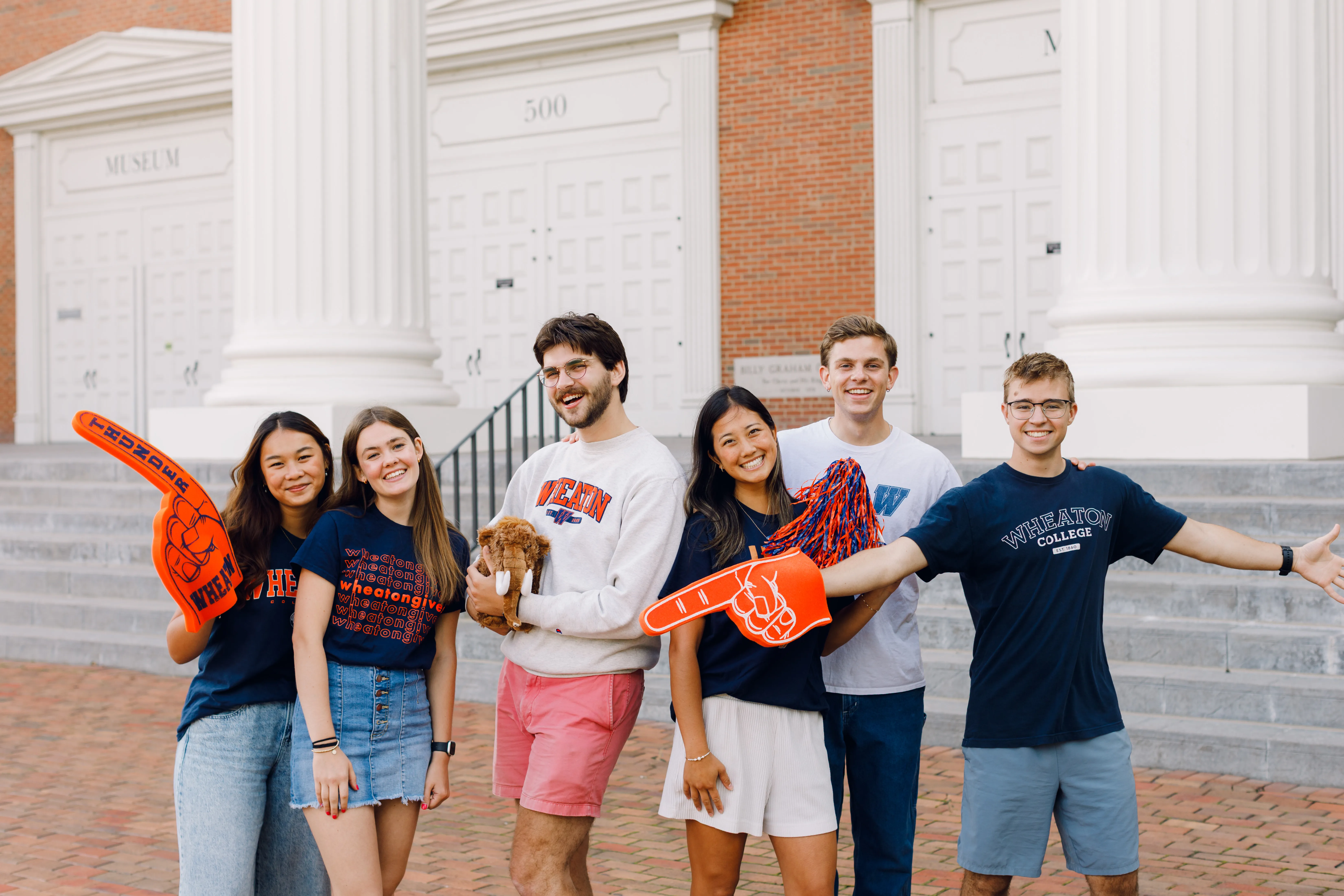 Six Wheaton students smiling in Wheaton gear.