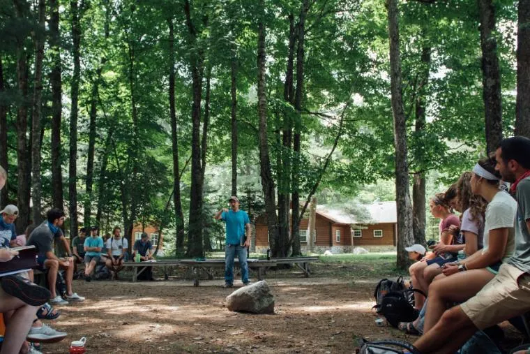 An outdoor meeting of young people with a man standing and speaking