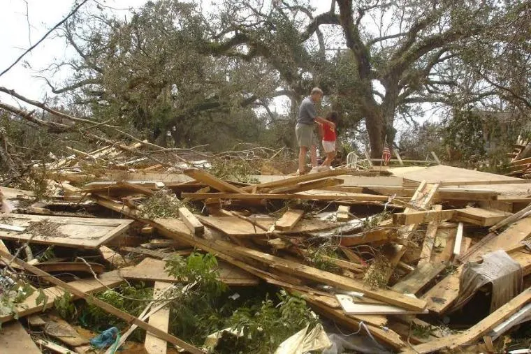 people walking by a demolished house