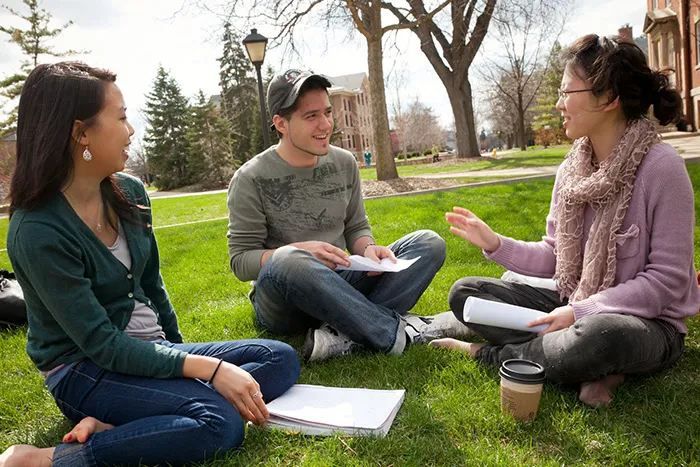 Photo of students sitting on lawn talking for left align content