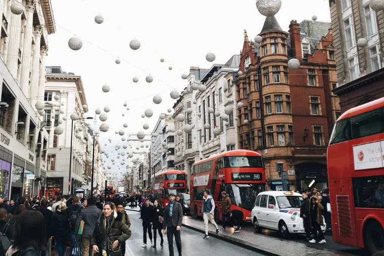 Busy street scene of double decker buses in London, with lanterns hanging overhead