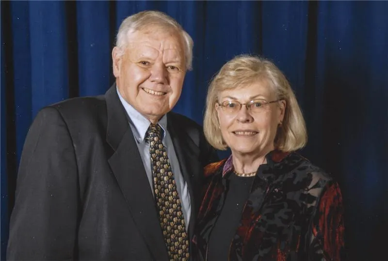 Michael and Elaine Jordan smiling at the camera in front of a blue background.
