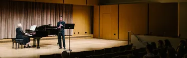 student on stage playing clarinet with accompanying piano