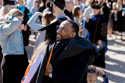 Graduate School Commencement, student hugging loved one