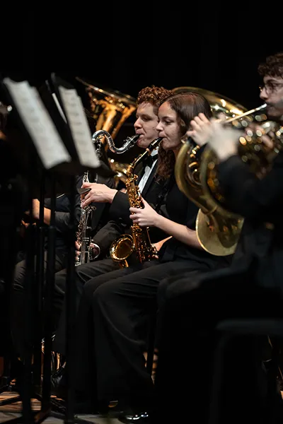 Students playing brass and woodwind instruments during a performance.