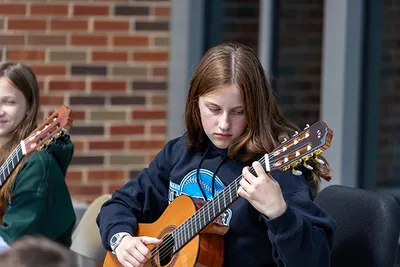 A teen girl playing guitar