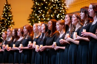 women singing and holding candles at the Christmas Festival