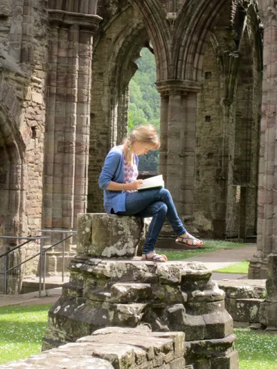 Student reading in cathedral ruins on Wheaton in England