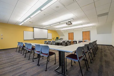 A room with tables, chairs, and a screen