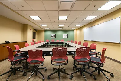 A room with tables, chairs, and a large white board