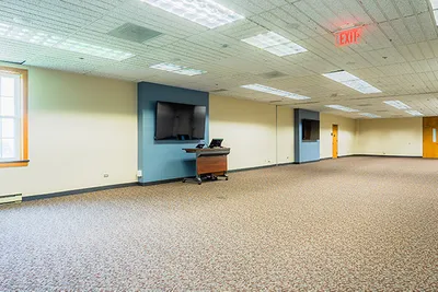 A spacious room with carpet and two tv screens