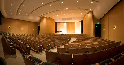 Empty auditorium with rows of seats facing a stage with a grand piano
