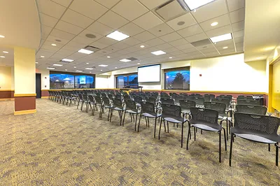 A room with a presentation screen and a few rows of chairs