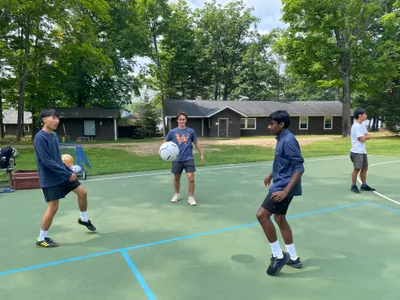 Three students playing soccer at Honey Rock.