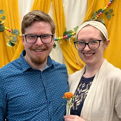 Chris and Katie Easley smiling together in front of a yellow floral background.