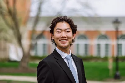 Christian Tai smiling at the camera in business formal.