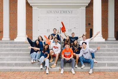A group of Wheaton students sitting on the steps outside of the Advancment doors of Billy Graham Hall.