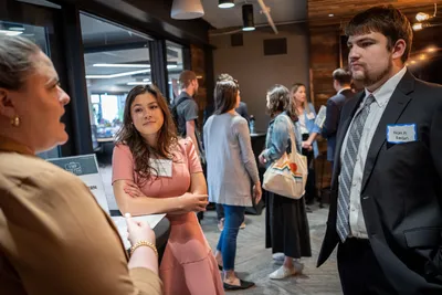 Two students talk with an alumna at a networking event in the CVC.