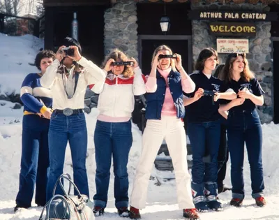 three people holding cameras taking photos in snow