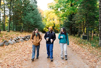 Three people with backpacks walking and talking on a trail