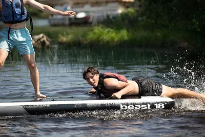 A man trying to balance himself on a stand-up paddleboard
