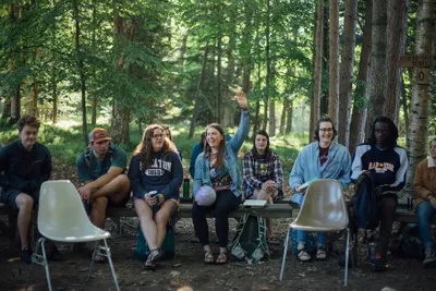 A group of people talking the in a forest