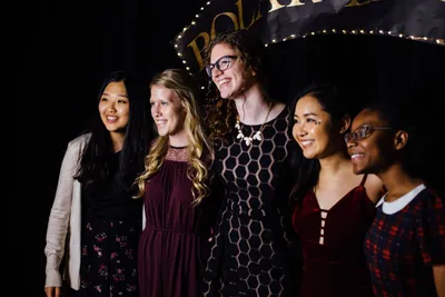 diverse group of female students smiling for a picture in front of Christmas banquet decorations