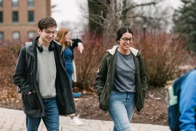 Two students walking to class and smiling outside