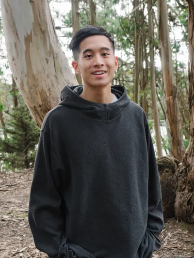 Elliot Young standing in front of trees and wearing dark gray hoodie