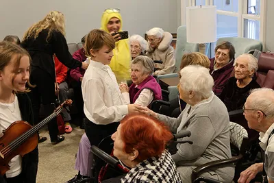 A boy smiles, holding hands with an older woman