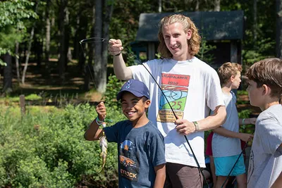 A boy and his camp leader show a fish they caught