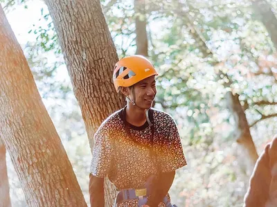 A male with helmet smiling by trees