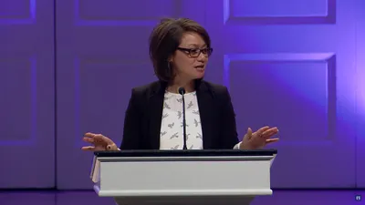 Filipina staff member speaking in Edman Chapel behind lectern