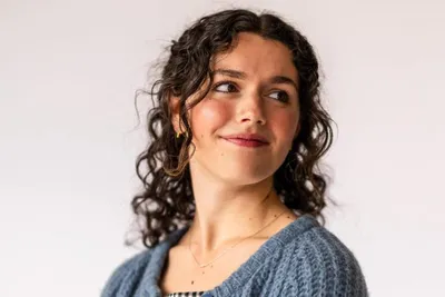 Doctoral student wearing a blue sweater and black and white gingham dress - Wheaton College Graduate School Bible and Theology Program