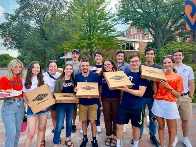 A group of student holding pizza boxes