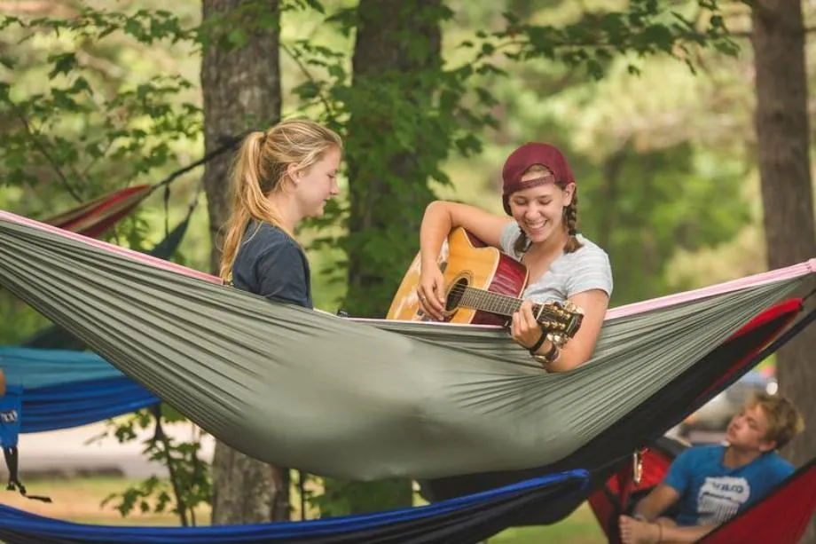 campers in hammock playing guitar