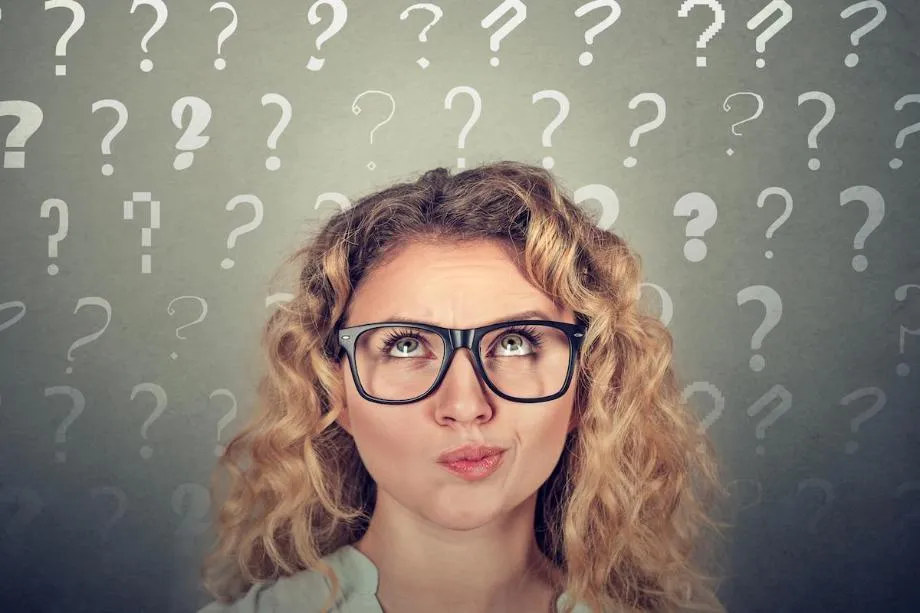 woman wearing glasses surrounded by question marks