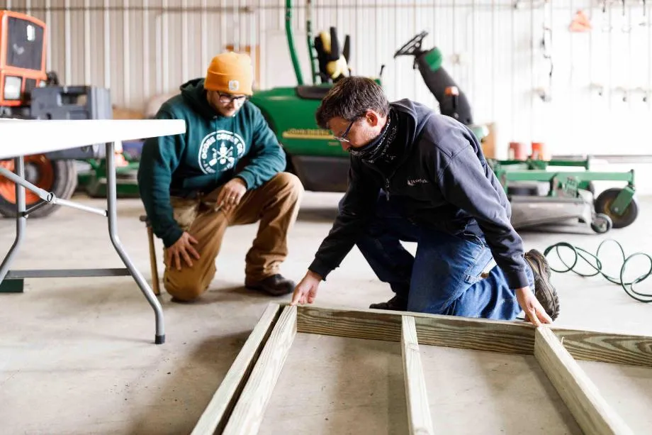 professional staff works with student to build a structure