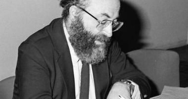 Black-and-white photo of Chaim Potok writing in a book, 1985