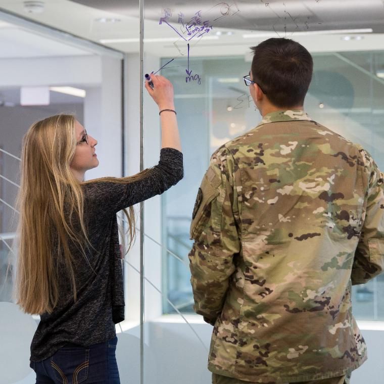 Engineering students completing equations on glass