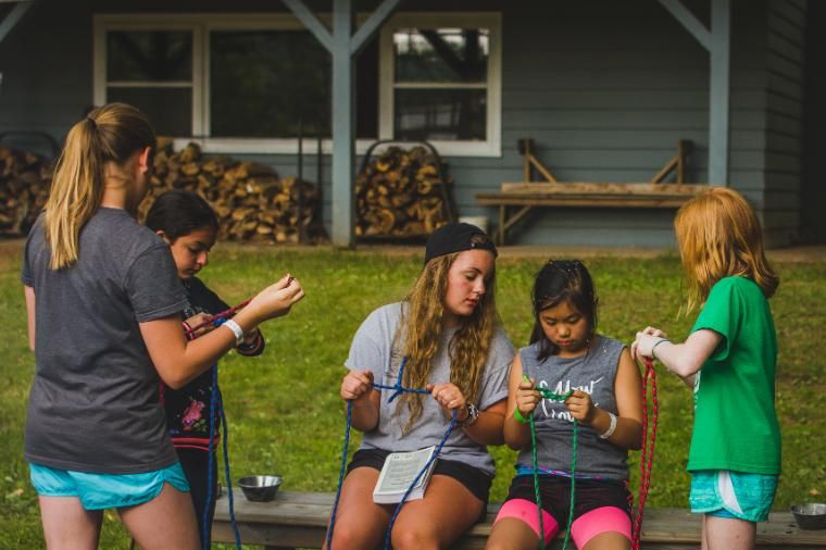 Evenings are a mix of structured activities and free time. Cabins play group games with "bro" or "sis" cabins, spend time around a campfire, participate in a creative activity, or hang out by the lake and talk. It's simply time to be with others in the great outdoors. In this photo, a cabin of girls is learning how to tie knots.