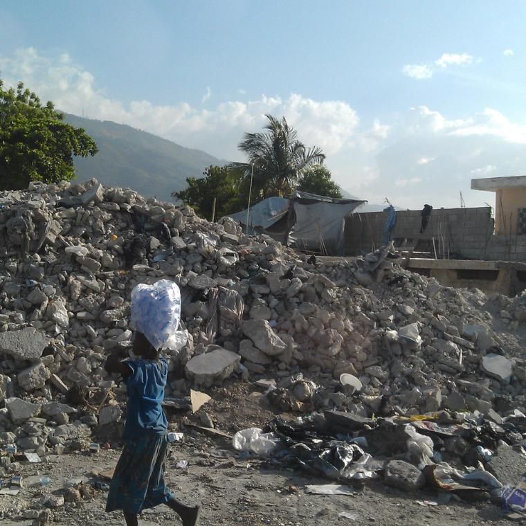 Boy balances bag on top of his head through rubble and fallen houses in Haiti after the earthquake