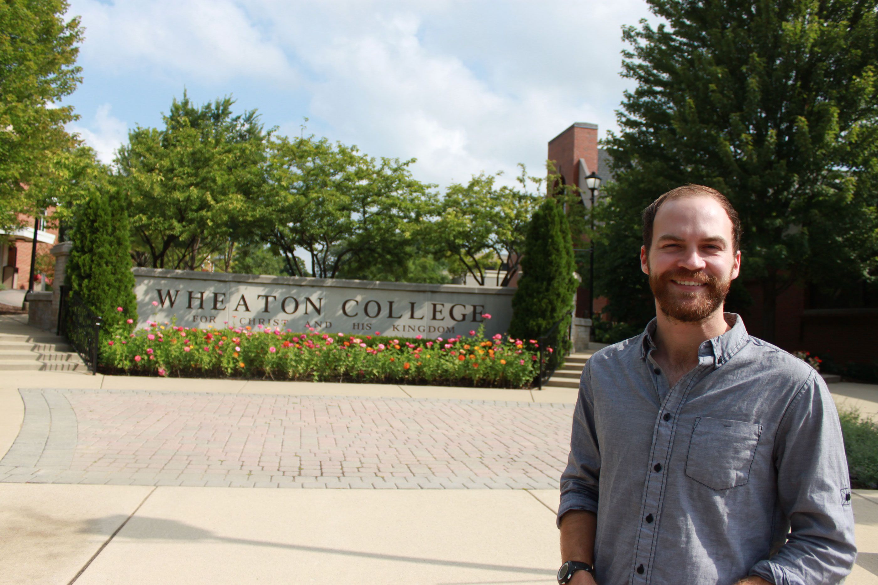Michael Sawyer standing at Wheaton College sign