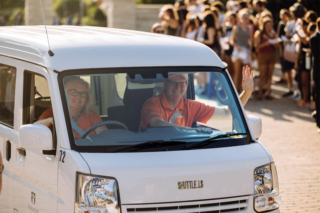 The Rykens greet first-year students from a Wheaton College van.