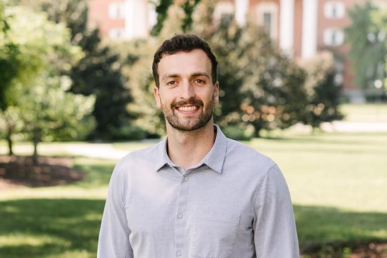 Man in button down shirt standing with Billy Graham Hall in the background