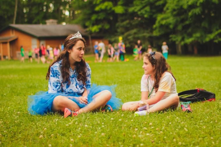 camper and counselor sit on the playing field at honeyrock in three lakes, wi