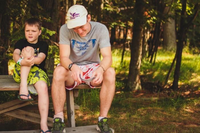 counselor and camper talk on wooden bench at HoneyRock in Three Lakes, WI