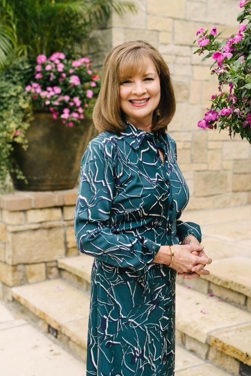 Woman in blue dress standing on steps in front of pink flowers