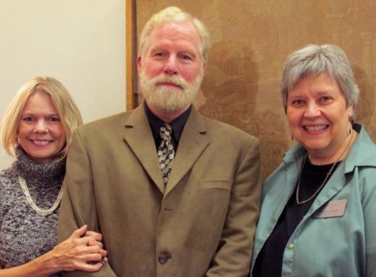 Man and 2 women surrounding him