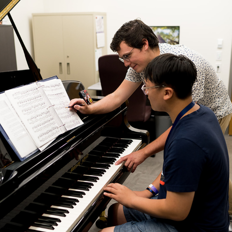 A teacher teaching a student by a piano